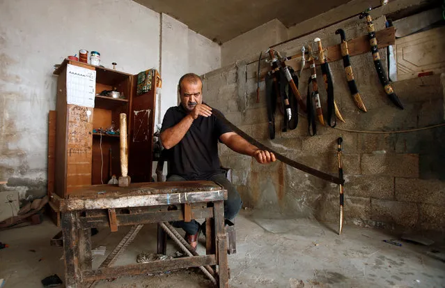 Palestinian blacksmith Mueen Abu Wadi, 45, checks the straightness of a sword in the process of making it at his workshop in Gaza City, as part of a job he inherited from his father and grandfather, November 14, 2016. (Photo by Suhaib Salem/Reuters)