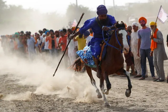 A Nihang, or a Sikh warrior, rides a horse as he performs during celebrations of Hola Mohalla, a festival of Nihangs, during Holi celebrations, at the site of a protest against farm laws, at Singhu border near New Delhi, India, March 29, 2021. (Photo by Adnan Abidi/Reuters)