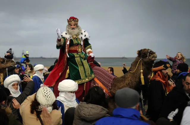A man dressed as one of the Three Wise Men greets children upon arriving at Poniente beach in Gijon, Spain, January 5, 2016. (Photo by Eloy Alonso/Reuters)