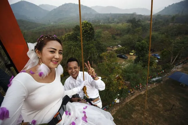 Groom Chaiyut Phuangphoeksuk and bride Prontathourn Pronnapatthun, smile for a photograph at the top of a climbing wall during their wedding ceremony at a resort in Ratchaburi province February 13, 2015. (Photo by Athit Perawongmetha/Reuters)