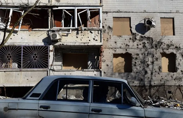 A man drives a car in front of a damaged building in Donetsk, on February 12, 2015. (Photo by Vasily Maximov/AFP Photo)