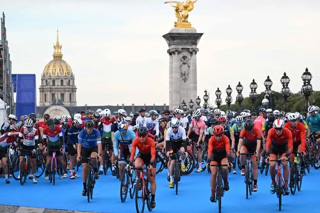 Triathlon athletes on their bikes take to the start at the Alexander III Bridge, during a familiarisation event on the eve of planned triathlon test races, in Paris on August 16, 2023. From August 17 to 20, 2023, Paris 2024 is organising four triathlon events to test several arrangements, such as the sports operations, one year before the Paris 2024 Olympic and Paralympic Games. (Photo by Bertrand Guay/AFP Photo)