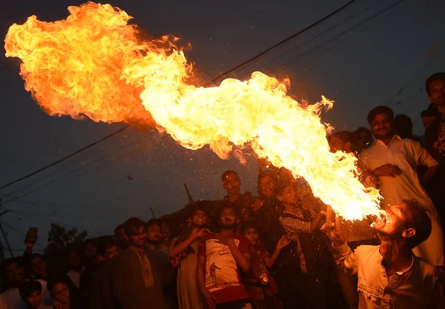 A Pakistani Sunni Muslim spits fire during an Ashura procession in Karachi on September 21, 2018. Ashura is a ten days period of mourning in remembrance of the seventh-century martyrdom of Prophet Mohammad's grandson Imam Hussein, who was killed in the battle of Karbala in modern-day Iraq, in 680 AD. (Photo by Rizwan Tabassum/AFP Photo)