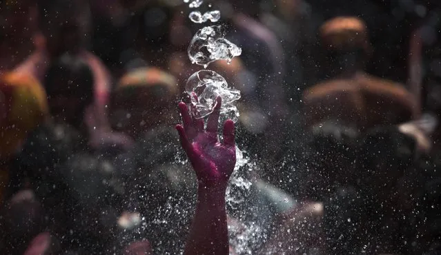 Water falls on the colored hand of a man, dancing during Holi celebrations in Gauhati, India, Friday, March 6, 2015. Holi, the Hindu festival of colors, also marks the advent of spring. (AP Photo/Anupam Nath)