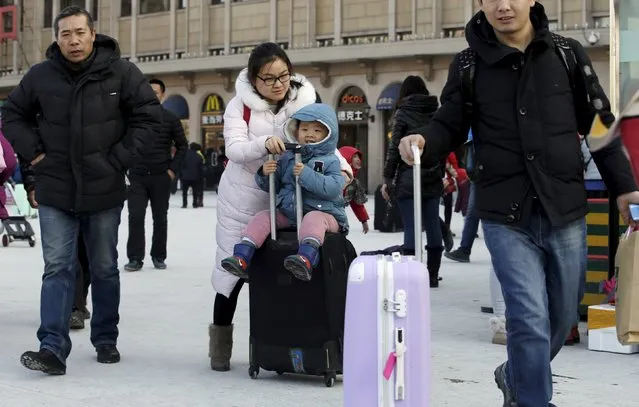 A mother pushes a bag carrying her 2.5-year-old son next to her husband (R) as the family arrive at Beijing Railway Station by train for Spring Festival, in Beijing, China, January 25, 2016. (Photo by Jason Lee/Reuters)