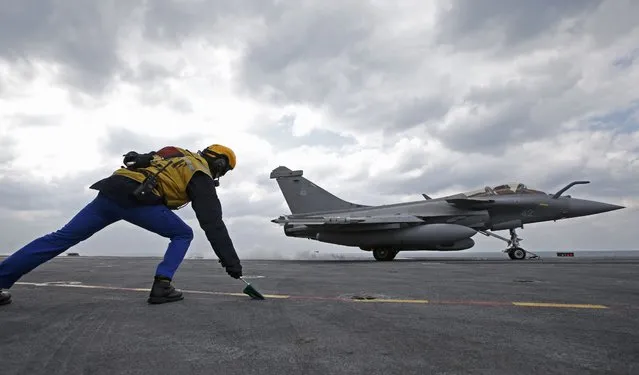 A “Yellow dog” flight deck director signals to the pilot of a Rafale fighter jet to taken off aboard France's Charles de Gaulle aircraft carrier in the Gulf, January 29, 2016. (Photo by Philippe Wojazer/Reuters)