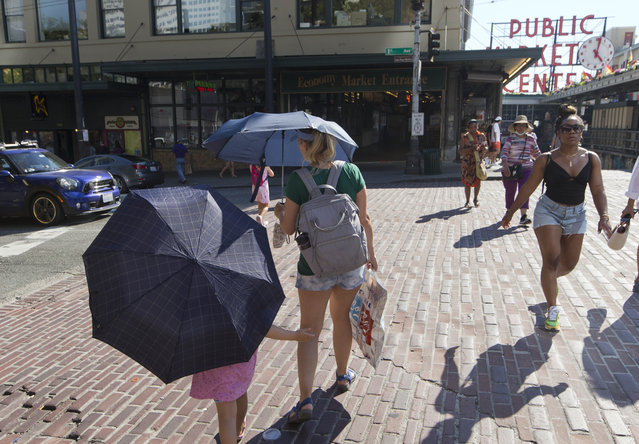 Sabina Ehmann and her daughter Vivian, visiting Seattle from North Carolina, are prepared with umbrellas to shield the sun during a heat wave hitting the Pacific Northwest, Sunday, June 27, 2021, in Seattle. Yesterday set a record high for the day with more record highs expected today and Monday. (Photo by John Froschauer/AP Photo)