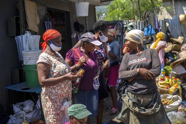 Customers wearing protective face masks as a precaution against the spread of the new coronavirus, talk with a vendor in a street market in Port-au-Prince, Haiti, Saturday, June 5, 2021. (Photo by Joseph Odelyn/AP Photo)