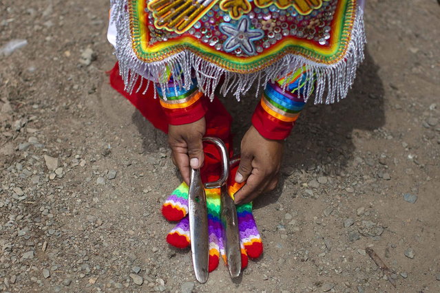 A "scissors" dancer known as Rey Chicchi pick up his scissors before performing in a national scissors dance competition in the outskirts of Lima December 1, 2013. (Photo by Enrique Castro-Mendivil/Reuters)