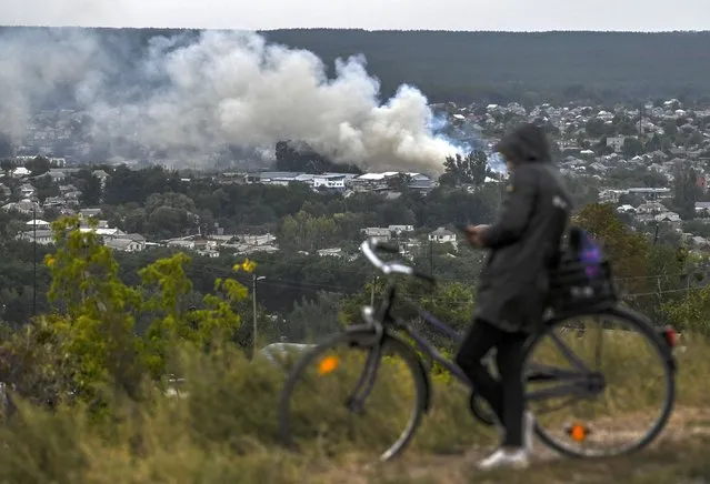 This photograph taken on September 11, 2022, shows a cyclist looking at a smartphone on a hill overlooking Izyum, Kharkiv Region, eastern Ukraine, amid the Russian invasion of Ukraine. Ukraine forces said that their lightning counter-offensive took back more ground in the past 24 hours, as Russia replied with strikes on some of the recaptured ground. The territorial shifts were one of Russia's biggest reversals since its forces were turned back from Kyiv in the earliest days of the nearly seven months of fighting, yet Moscow signalled it was no closer to agreeing a negotiated peace. (Photo by Juan Barreto/AFP Photo)