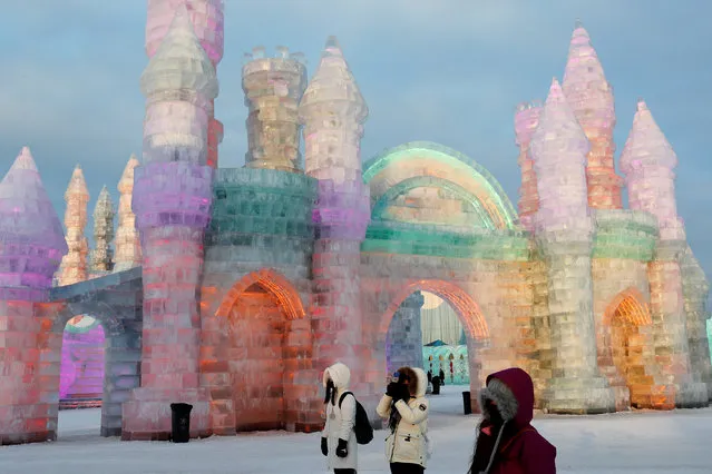 Visitors stand in front of ice sculptures illuminated by colored lights at the annual ice festival, in the northern city of Harbin, Heilongjiang province, China on January 4, 2019. (Photo by Tyrone Siu/Reuters)