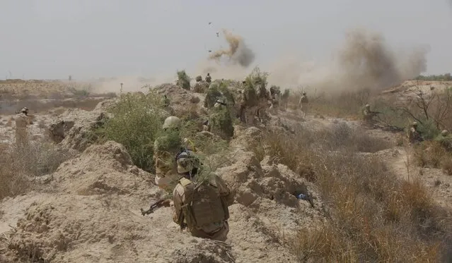 Iraqi security forces walk with thier weapons while smoke rises from a mock bomb as part of military training in Jurf al-Sakhar, Iraq April 9, 2015. (Photo by Alaa Al-Marjani/Reuters)