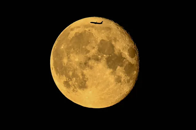 A plane is silhouetted behind Waning Gibbous moon in Moscow late on July 25, 2021. (Photo by Kirill Kudryavtsev/AFP Photo)