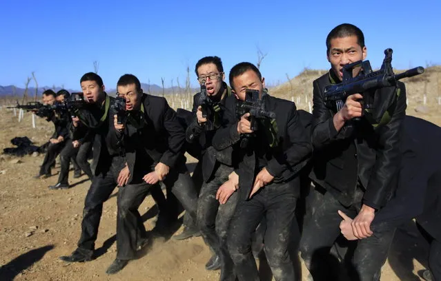 Students holding replica 95 semi-automatic rifles practice protecting their employers at a shooting training field managed by the military during Tianjiao Special Guard/Security Consultant training on the outskirts of Beijing December 14, 2013. (Photo by Jason Lee/Reuters)