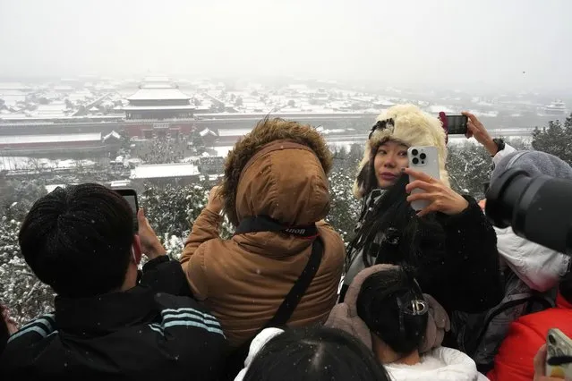 A woman turns back for a selfie with the snow covered Forbidden City from a hilltop pavilion in Jingshan Park in Beijing, Wednesday, December 13, 2023. (Photo by Ng Han Guan/AP Photo)