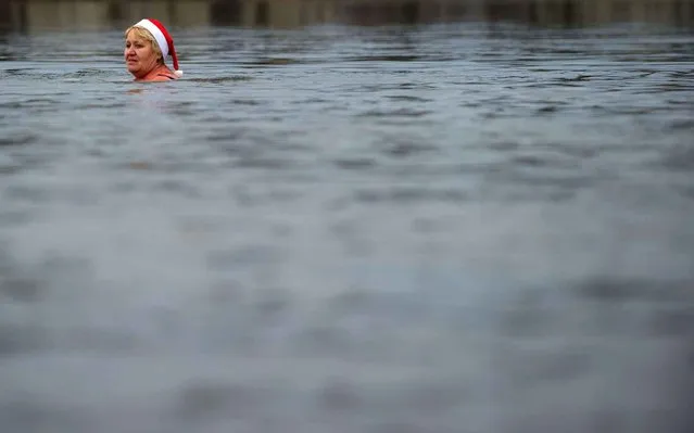 A costumed member of the “Berlin Seals” swims in Lake Orankesee in Berlin, Germany Wednesday December 25, 2013. Traditionally the group meets for swimming on Christmas Day. (Photo by Tim Brakemeier/AP Photo/DPA)