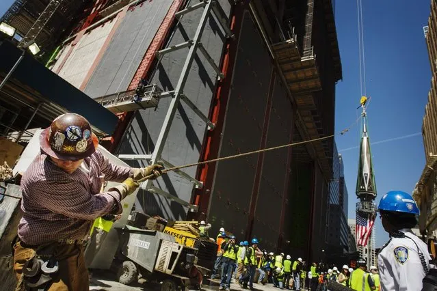 An ironworker uses a line to steady the final piece of a spire, affixed with a U.S. flag, before it is lifted to the top of One World Trade Center in New York, May 2, 2013. (Photo by Lucas Jackson/Reuters)