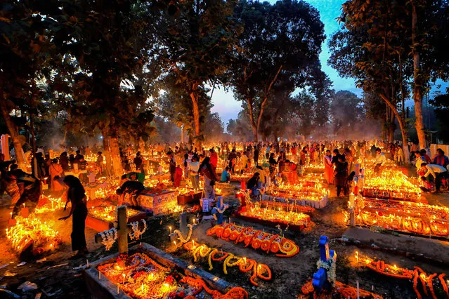 Christian devotees offer prayers next to the graves of their deceased family members during All Souls' Day at a cemetery in Nadia, India on November 2, 2022. Christian devotees gather at the graves of their loved ones at a cemetery with lit up candles and flowers during the All Souls' Day. A day when Christians remember their friends & relatives, who have passed away. This comes from an ancient belief that the souls of the dead will return, on this particular day, to have a meal with their family & friends. Candles are lit to guide the souls to their home for the meal. (Photo by Avishek Das/SOPA Images via ZUMA Press Wire)