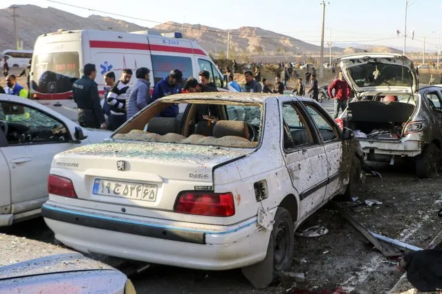 People stay next to destroyed cars after an explosion in Kerman, Iran, Wednesday, January 3, 2024. Iran says bomb blasts at an event honoring a prominent Iranian general slain in a U.S. airstrike in 2020 have killed at least 103 people and wounded 188 others. (Photo by Tasnim News Agency via AP Photo)