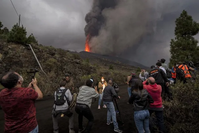 Journalists report during a media tour near the volcano on the island of La Palma in the Canaries, Spain, Wednesday, September 22, 2021. A volcano on a small Spanish island in the Atlantic Ocean erupted on Sunday, forcing the evacuation of thousands of people. Experts say the volcanic eruption and its aftermath on a Spanish island could last for up to 84 days. The Canary Island Volcanology Institute said Wednesday it based its calculation on the length of previous eruptions on the archipelago. (Photo by Emilio Morenatti/AP Photo)