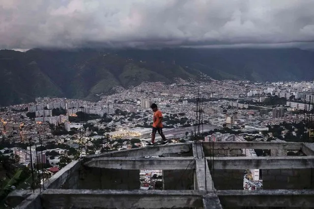 A boy walks on an unfinished house in the El Quilombo neighborhood of Caracas, Venezuela, Saturday, September 25, 2021. (Photo by Matias Delacroix/AP Photo)