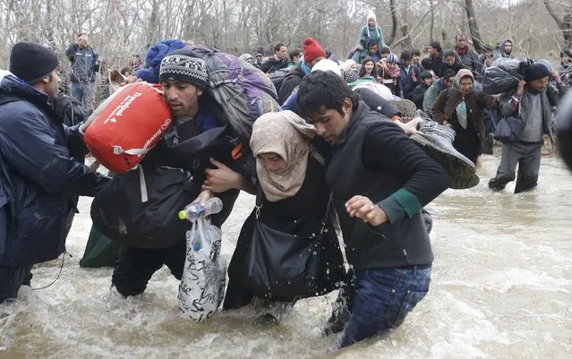 Migrants wade across a river near the Greek-Macedonian border, west of the the village of Idomeni, Greece, March 14, 2016. (Photo by Stoyan Nenov/Reuters)