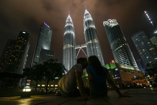 Tourists kissing front of Malaysia's landmark Petronas Twin Towers with lights on before turned off to mark Earth Hour 2016 in Kuala Lumpur, Malaysia, 19 March 2016. Earth Hour takes place worldwide at 8.30 p.m. local time and is a global call to turn off lights for 60 minutes to raise awareness of the danger of global climatic change  (Photo by Fazry Ismail/EPA)