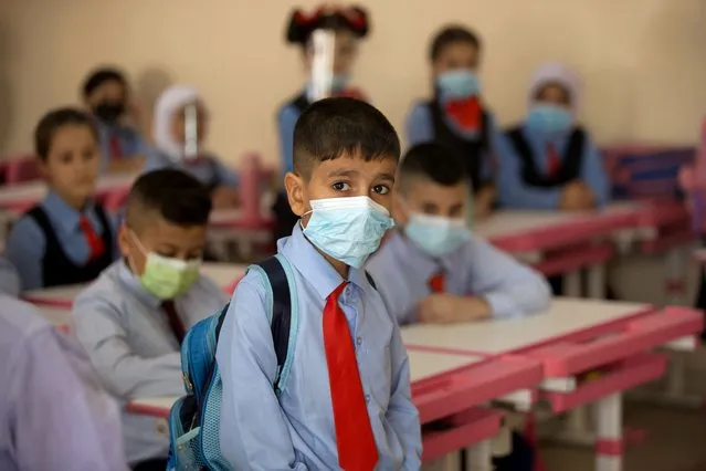Students wear face masks in their classroom, in Baghdad, Iraq, Monday, November 1, 2021. Across Iraq, students returned to classrooms Monday for the first time in a year and a half – a stoppage caused by the coronavirus pandemic – amid overcrowding and confusion about COVID-19 safety measures. (Photo by Hadi Mizban/AP Photo)