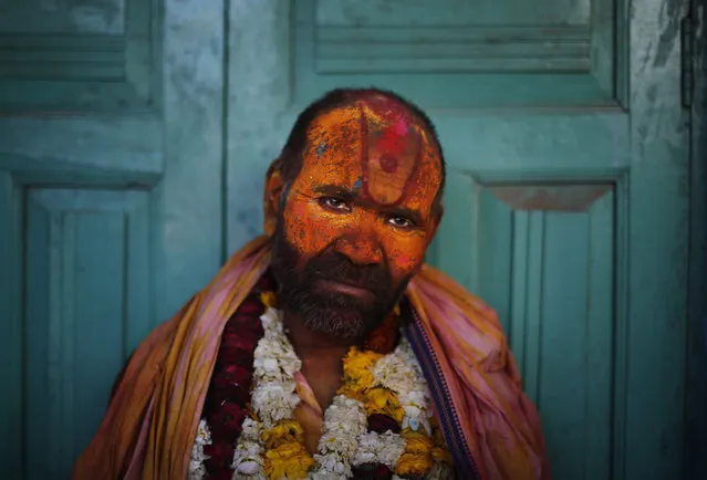 A Sadhu or Hindu holy man leans against a closed door at the Nandagram Temple famous for Lord Krishna during Lathmar Holi festival in Nandgaon 120 kilometers ( 75 miles) from New Delhi, India, Monday, March 10, 2014. (Photo by Altaf Qadri/AP Photo)