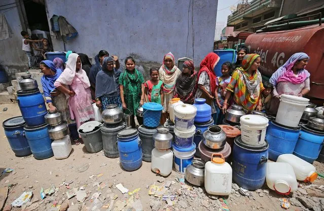 Local residents wait in a queue to collect drinking water from a municipal corporation water tanker on a hot summer day in the outskirts of Ahmedabad, India, May 1, 2019. (Photo by Amit Dave/Reuters)