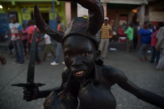 A boy with his body painted with a mixture of cane sugar syrup and coal depicting the devil while performs in the third and final day of Carnival in the capital of Haiti, Port- au- Prince, on February 28, 2017. (Photo by Hector Retamal/AFP Photo)