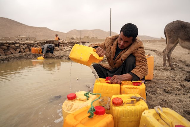 Afghan man fills oil canisters with water near the improvised dam, in Hachka, Afghanistan, Monday, December. 13, 2021. Severe drought has dramatically worsened the already desperate situation in Afghanistan forcing thousands of people to flee their homes and live in extreme poverty. Experts predict climate change is making such events even more severe and frequent. (Photo by Mstyslav Chernov/AP Photo)