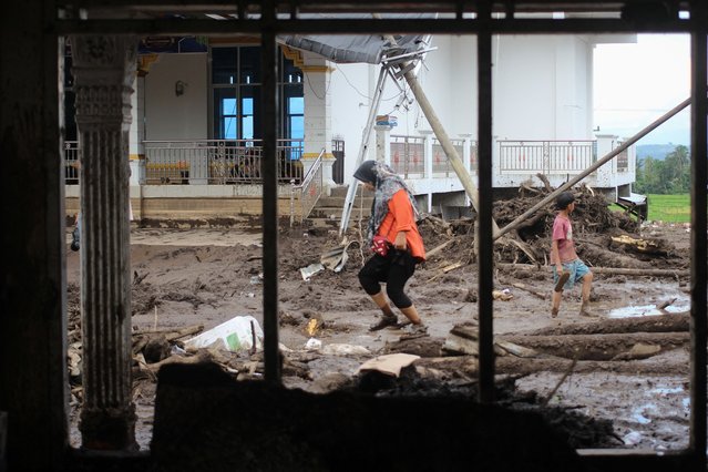 People walk in the mud following deadly flash floods and cold lava flow in Tanah Datar, West Sumatra, on May 13, 2024. The death toll from flash floods and cold lava flow from a volcano in western Indonesia over the weekend has risen to 44 with 15 more missing, officials said on May 13. (Photo by Ade Yuandha/AFP Photo)