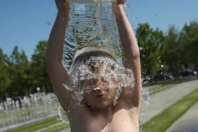 Paul, 9, dumps a bucket of water over his head at a fountain near government buildings during hot weather on July 1, 2015 in Berlin, Germany. Temperatures across northern Europe are rising and in Germany a high of 36 degrees is forecast for the weekend. (Photo by Sean Gallup/Getty Images)