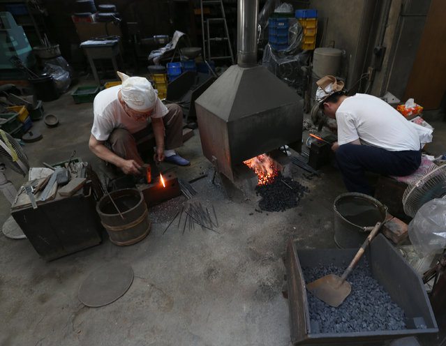 A master Myouchin Munemichi (L), 72, and his son Myouchin Keizo, 38, as they produce Hbashi iron bells made of iron at Myochin Honpo shop on April 25, 2014 in Himeji, Japan. (Photo by Buddhika Weerasinghe/Getty Images)