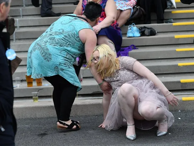 One woman is helped up by a friend after falling over during the Grand National Festival at Aintree Racecourse on April 6, 2017 in Liverpool, England. (Photo by News Group Newspapers Ltd)