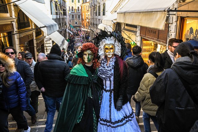 Masked revellers in period costume pose at the Rialto bridge on February 11, 2023 in Venice during the carnival. (Photo by Miguel Medina/AFP Photo)