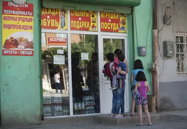 People gather near a shop, with bottles of Borjomi bottled mineral water seen behind a window, in Leningori (or Akhalgori), in the breakaway region of South Ossetia, Georgia, July 6, 2015. (Photo by Kazbek Basaev/Reuters)