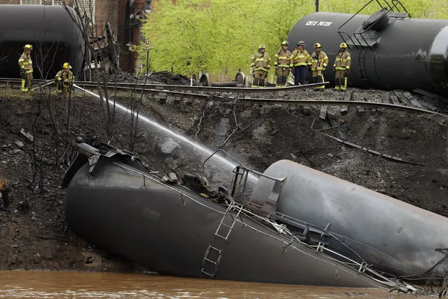 Firefighters and rescue workers work along the tracks where several CSX tanker cars carrying crude oil derailed and caught fire along the James River near downtown in Lynchburg, Va., Wednesday, April 30, 2014. Police said that more than a dozen tanker cars were involved in the derailment. (Photo by Steve Helber/AP Photo)