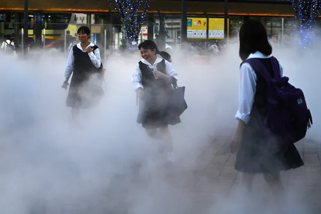 Students walk through smoke generated from a machine in Oita on October 10, 2019, which will host two quarter-final matches in the Japan 2019 Rugby World Cup. Two Rugby World Cup matches have been cancelled for the first time in the tournament's history as Japan braces for potential damage and disruption from powerful Super Typhoon Hagibis. (Photo by Gabriel Bouys/AFP Photo)