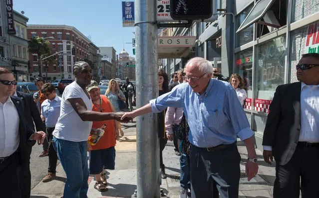 Democratic presidential candidate Bernie Sanders shakes hands with a man holding a beer while taking a walk through San Francisco, California on May 18, 2016. (Photo by Josh Edelson/AFP Photo)