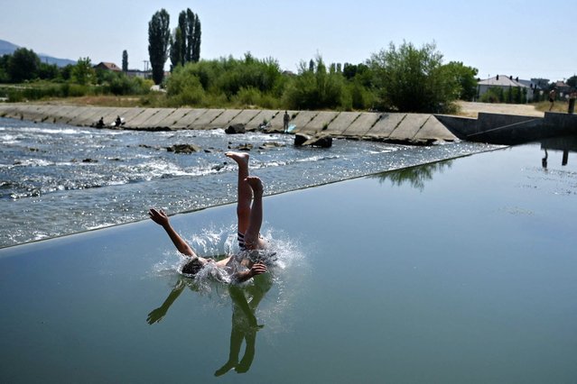 A boy jumps into the Iber river to cool off in Mitrovica on July 17, 2024. A heat wave sweeps the country for the eighth day in a row with temperatures reaching 40 degrees. (Photo by Armend Nimani/AFP Photo)