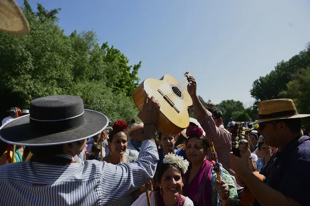 A pilgrim passes a guitar to another as they cross the Quema river during the annual El Rocio pilgrimage in Villamanrique, near Sevilla on June 1, 2017. (Photo by Cristina Quicler/AFP Photo)
