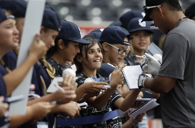 Softball player Annika Mitosinka of El Centro, Calif., center, gets a signature from San Diego Padres second baseman Yangervis Solarte before the Padres' baseball game against the Colorado Rockies on Friday, June 2, 2017, in San Diego. (Photo by Gregory Bull/AP Photo)