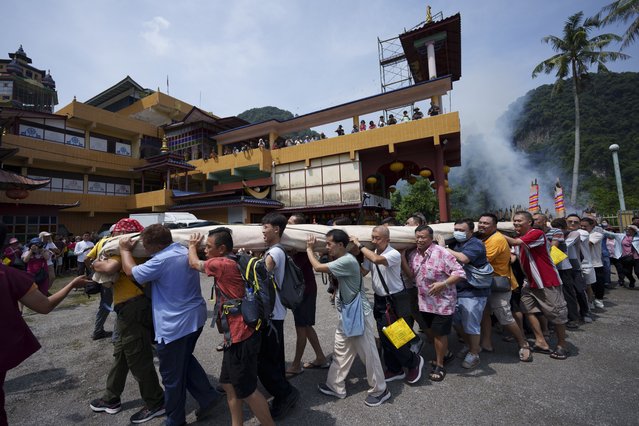 Devotees carries a giant canvas of sacred “Thangka” to display under the sun during Wesak day celebration in Ipoh, Malaysia, Wednesday, May 22, 2024. (Photo by Vincent Thian/AP Photo)