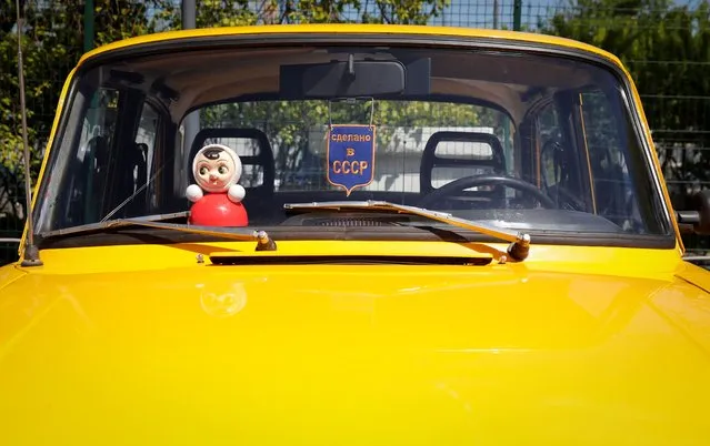 A Roly Poly Nevalyashka doll is seen inside a car during a gathering of Soviet-era Moskvich cars owners and enthusiasts in Moscow, Russia on May 21, 2022. The sign reads: “Made in USSR”. (Photo by Shamil Zhumatov/Reuters)