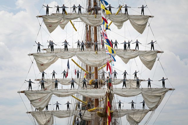 Sailors stand on the sails of the the Cuauhtemoc as the ship leaves Rouen, northwestern France, during the Big parade during the end of the Armada 2023 event, on June 18, 2023. (Photo by Lou Benoist/AFP Photo)