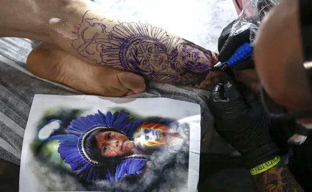 A tattoo artist makes a tattoo on the leg of a woman during the Tattoo Week in Sao Paulo, Brazil, July 14, 2017. (Photo by Miguel Schincariol/AFP Photo)