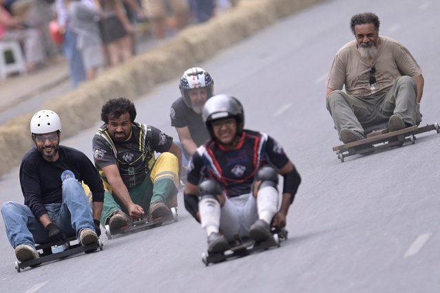 Soapbox cart riders race downhill during the 10th edition of the Rolima do Abacate event during the Virada Cultural festival in Belo Horizonte, state of Minas Gerais, Brazil, on August 20, 2023. (Photo by Douglas Magno/AFP Photo)