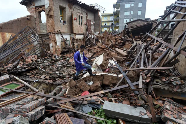 In this July, 9, 2016 photo released by Xinhua News Agency, a man walks past damaged houses following Typhoon Nepartak hit Putian city in southeast China's Fujian province. Several people dead and missing after Typhoon Nepartak battered China's coastal Fujian Province with heavy rain and strong winds that toppled homes and triggered landslides, government agencies said. (Photo by Zhang Guojun/Xinhua via AP Photo)